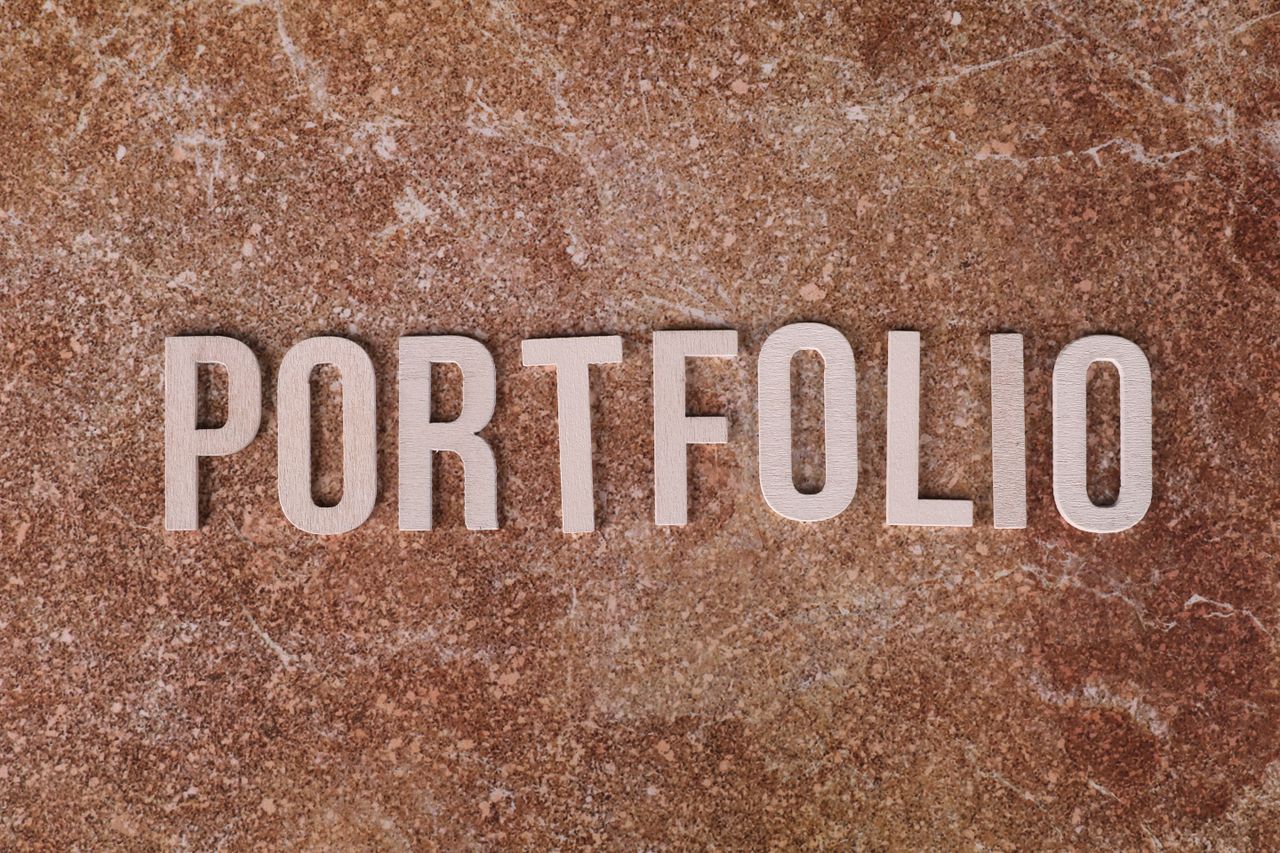 Home Metallic 'PORTFOLIO' letters on textured brown marble surface. Ideal for presentations.