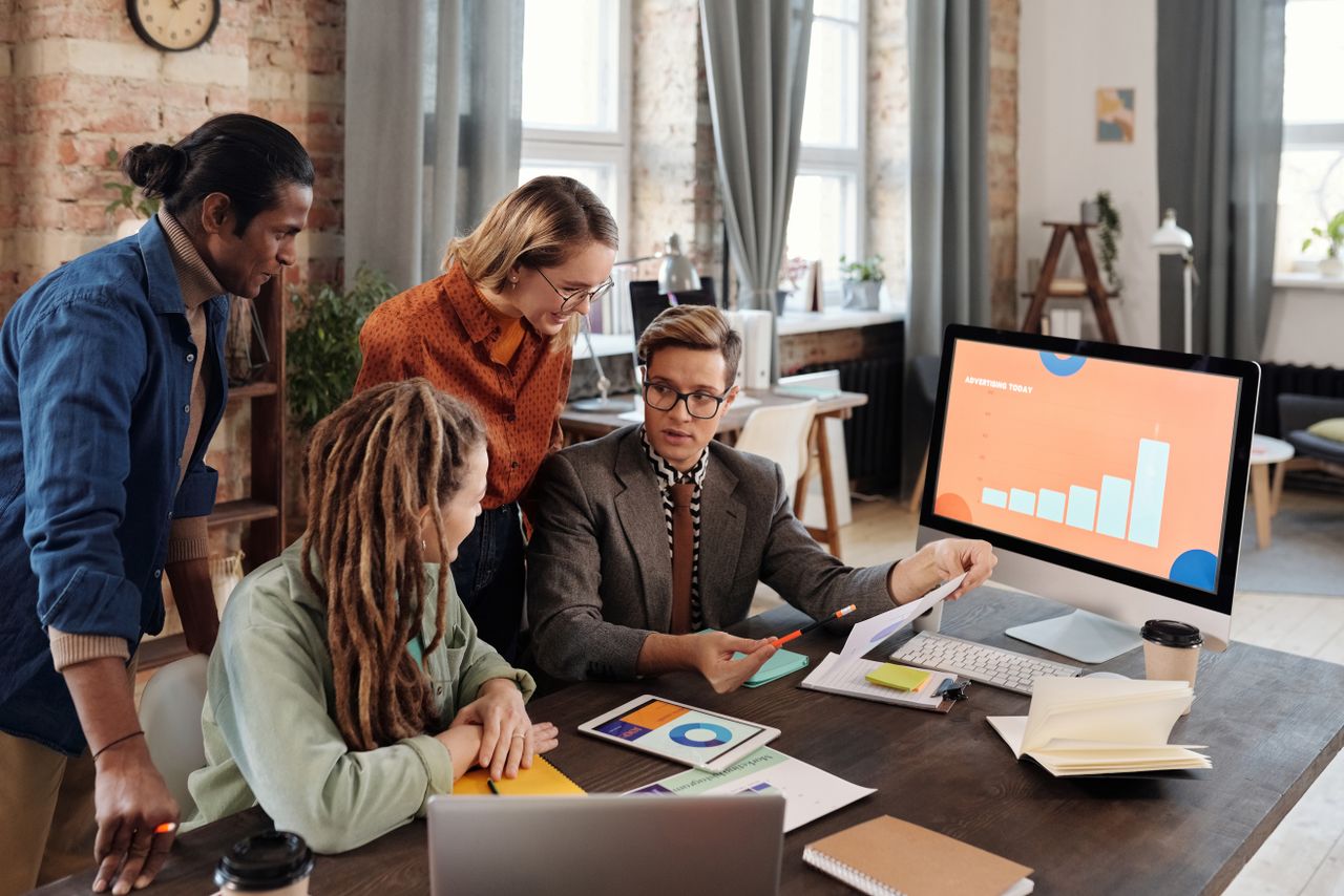 A group of diverse professionals discussing digital marketing plans in a modern office setting.
